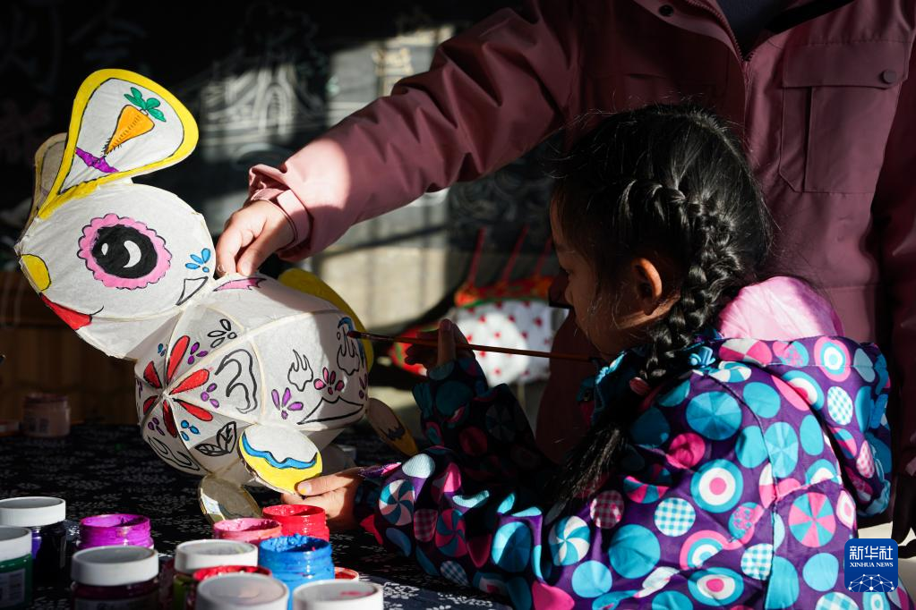 Seorang budak perempuan belajar membuat tanglung berbentuk arnab di Kampung Hongcun, provinsi Anhui pada 30 Jan 2023. (Gambar oleh Du Yu dari Xinhua)