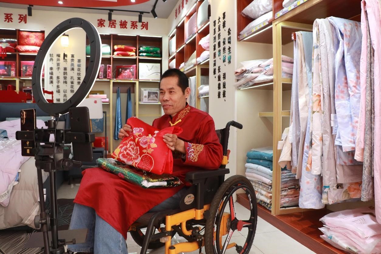Seorang lelaki yang berkekurangan dari segi mobiliti menjual produknya menerusi strim langsung di pekan Pangjia, Binzhou, provinsi Shandong di timur China. (People’s Daily Online/Shao Qiang)