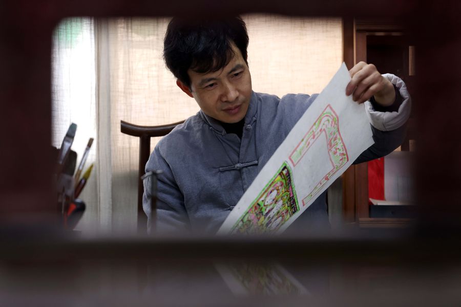 Foto menunjukkan Tong Min memeriksa karya luksiannya. (foto: Xie Chen/People.cn)