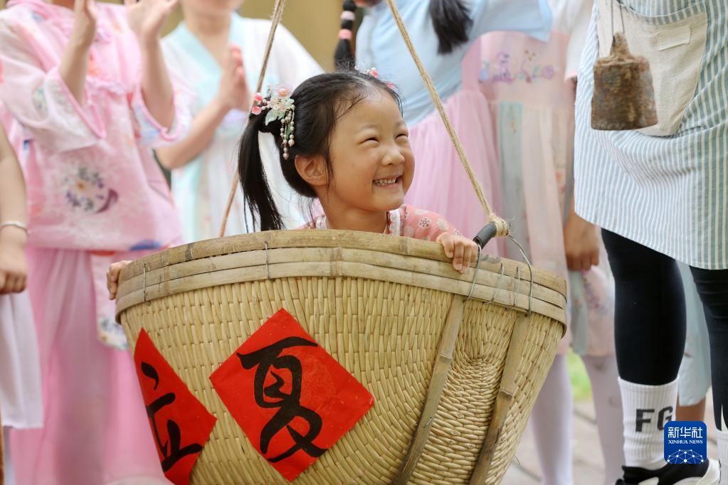 Timbang berat badan antara salah satu adat Hari Lixia. Gambar ini menunjukkan seorang cikgu tadika di Huzhou, Zhejiang, menimbang berat badan murid dengan cara tradisional pada 5 Mei. (Xinhua/Xie Shangguo)