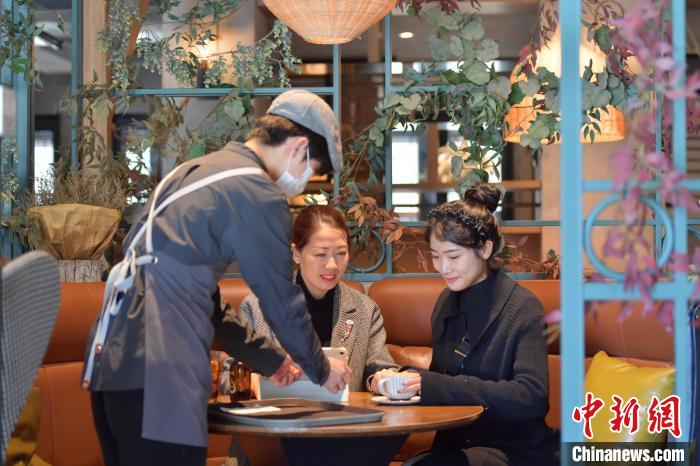 Pemilik kedai kopi, Zhang Yanhui(dua dari kiri) berborak dengan pelanggan. (Liu Dong)