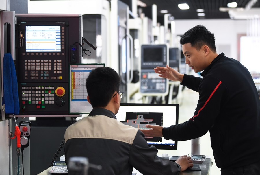 Seorang jurulatih vokasional menunjukkan cara mengendalikan peralatan mesin kepada pelajar di Kolej Juruteknik Jentera Guangdong di Guangzhou, selatan China, 14 Februari 2023. (Xinhua/Deng Hua)