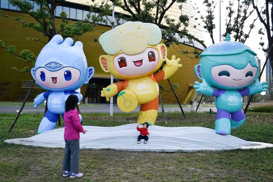 Seorang kanak-kanak perempuan bergambar dengan Chenchen, Congcong dan Lianlian (kiri ke kanan), maskot-maskot Sukan Asia 2022 Hangzhou, di Pusat Sukan Terusan Gongshu, provinsi Zhejiang, timur China, 9 November 2021. (Xinhua/Huang Zongzhi)