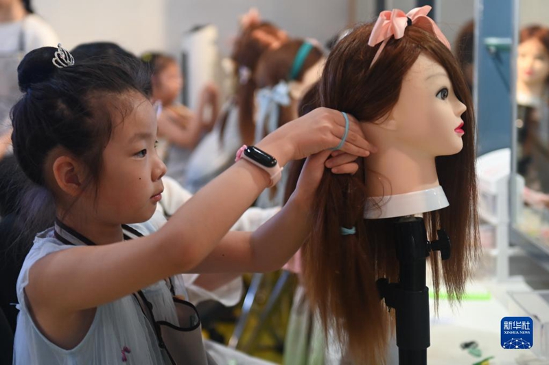 Pada 9 Julai, budak-budak menyertai aktiviti mengenali kerjaya pendandan rambut. (foto: Huang Zongzhi/Xinhua)