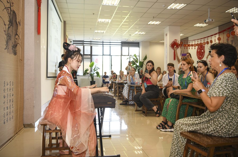 Ahli rombongan penari asing menonton persembahan guzheng, sejenis ziter Cina, di Perpustakaan Xinjiang, Urumqi, wilayah autonomi Uygur Xinjiang di barat laut China pada 23 Julai 2023. (Xinhua/Hu Huhu)