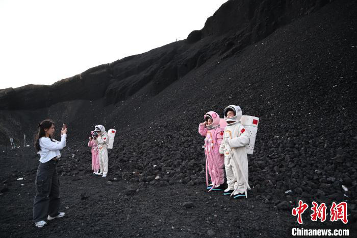 Di bandar Ulanqab, Mongolia Dalam, pelancong memakai "sut angkasa" dan mengambil gambar di gunung berapi Ulan hada. (foto: Liu Wenhua/Chinanews.cn)