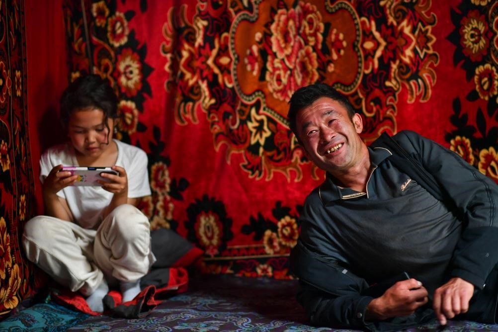 Muxtar bersama anak perempuan bongsunya berehat di dalam yurt pada 14 Ogos. (Xinhua/Hu Huhu)