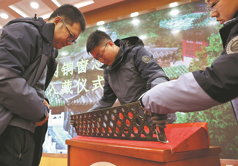 Pakar memeriksa panel kekisi gangsa yang dikembalikan ke Istana Musim Panas di Beijing semasa upacara pada Rabu. (China Daily/Jiang Dong)