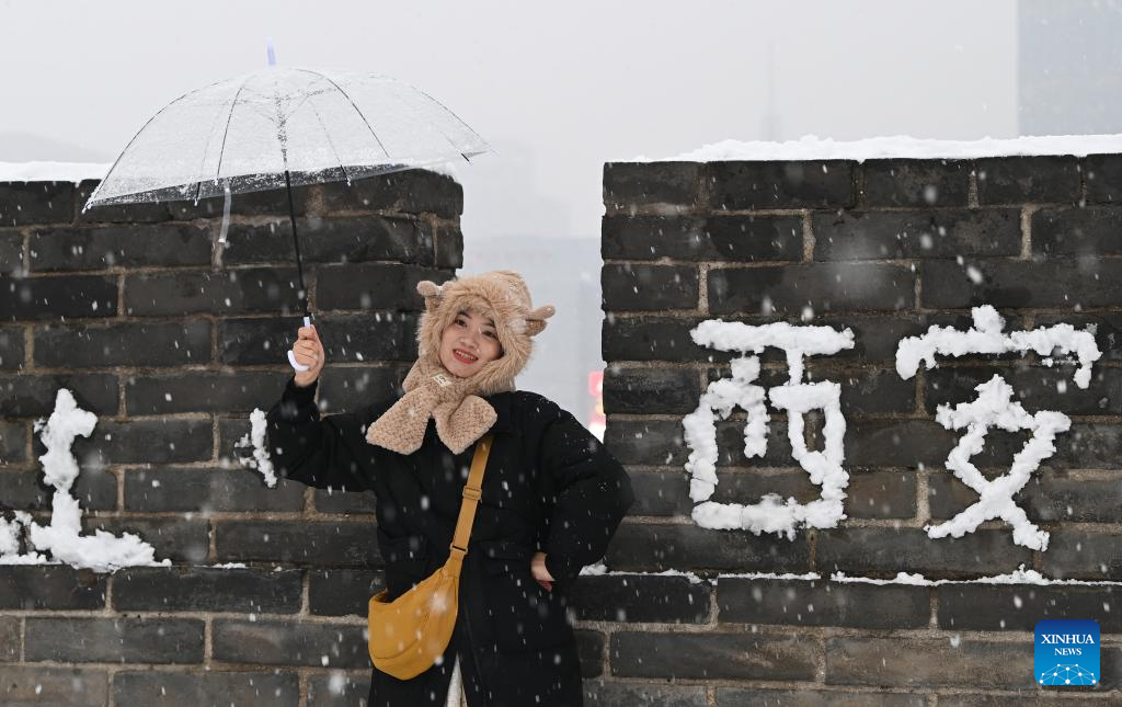 Seorang pelancong menikmati pemandangan di atas tembok kota purba yang dilitupi salji di Xi’an, provinsi Shaanxi, barat laut China, 16 Januari 2024. (Xinhua/Liu Xiao)