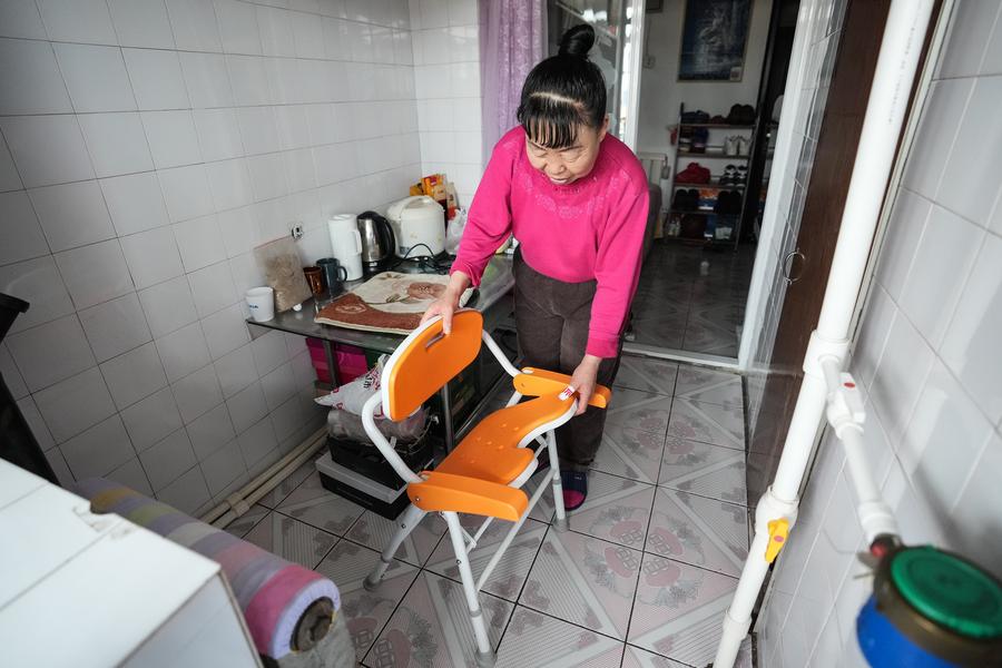 Wang Yingqiu mengatur kerusi mandi di rumahnya di daerah Sujiatun, Shenyang, provinsi Liaoning, timur laut China, 20 Februari 2024. (Xinhua/Pan Yulong)