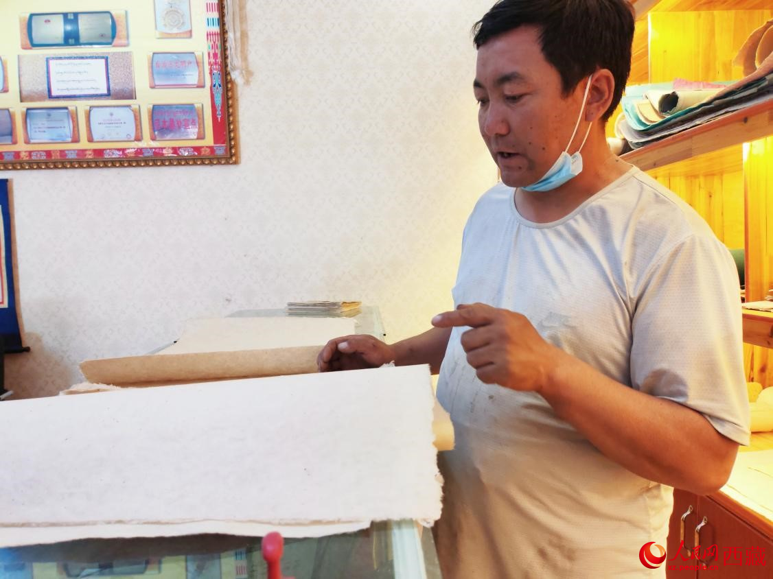 Phuchung, salah seorang pewaris pembuatan kertas Tibet sedang menyediakan kertas Tibet untuk dijual. (People’s Daily Online/Li Haixia)