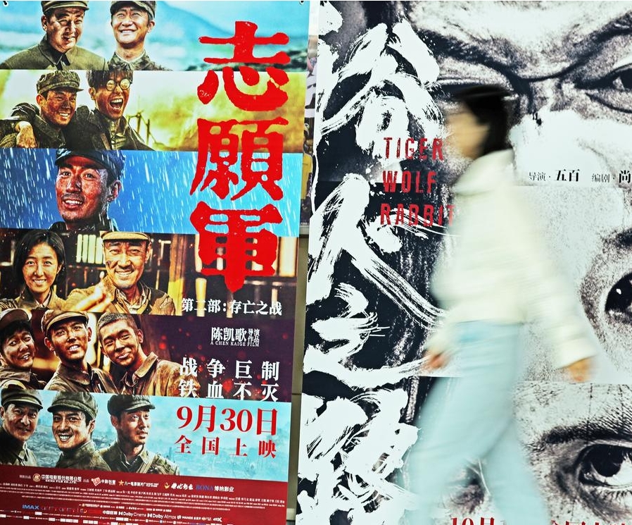 Foto seorang wanita melintasi poster filem di sebuah pawagam di Kaunti Tancheng, Provinsi Shandong, timur China pada 7 Oktober 2024. (Foto Zhang Chunlei/Xinhua)