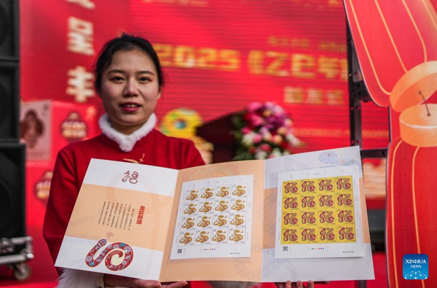 Seorang kakitangan menunjukkan setem istemewa Tahun Ular di sebuah pejabat pos di Guiyang, Provinsi Guizhou. (Xinhua/Tao Liang)