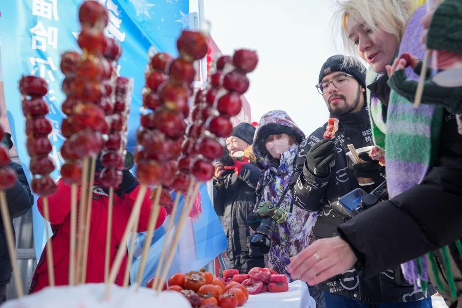 Pelancong asing mencuba snek pada festival mengumpul ais di Harbin, provinsi Heilongjiang, timur laut China, 7 Disember 2024. (Xinhua/Wang Jianwei)
