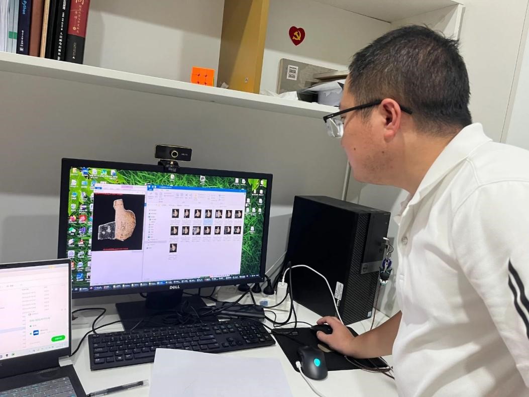 Seorang penyelidik menunjukkan bagaimana inskripsi tulang oracle disatukan dengan bantuan teknologi AI. (Foto ihsan Makmal Utama Kementerian Pendidikan China untuk Pemprosesan Maklumat Oracle di Universiti Anyang Normal)