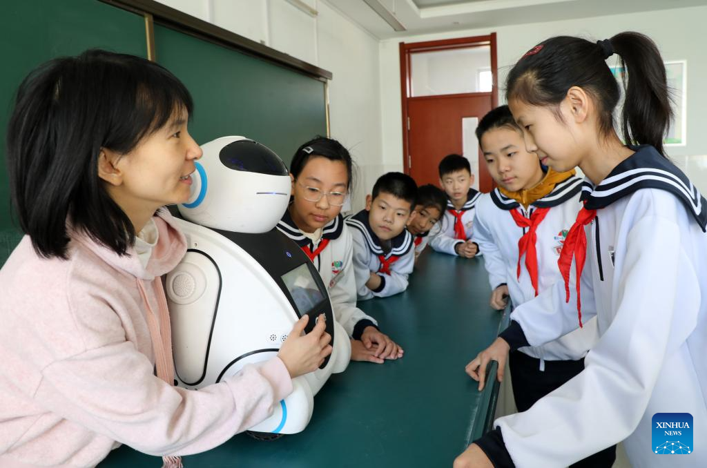 Seorang guru sedang memberi panduan kepada pelajar untuk berinteraksi dengan robot pintar di Sekolah Rendah No.1 di Kaunti Boxing, Provinsi Shandong, timur China. (Xinhua/Chen Bin)