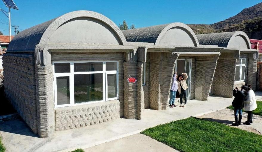 Pelancong bergambar di hadapan sebuah rumah ladang cetakan 3D di kampung Wujiazhuang, Zhangjiakou di Provinsi Hebei, utara China. (Foto oleh Chen Xiaodong)