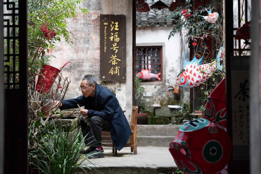 Seorang artis sedang menghasilkan tanglung berbentuk ikan di pekan purba Huizhou di Kaunti Shexian, Bandar Huangshan, Provinsi Anhui di timur China pada 23 Mac 2025. (Xinhua/Zhang Duan)