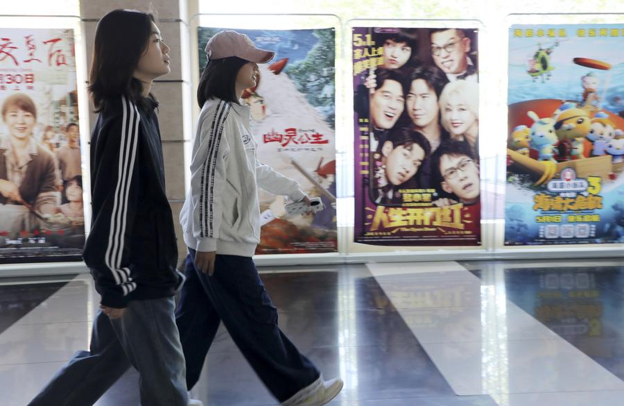 Orang ramai melintasi poster filem di sebuah pawagam di Kaunti Boxing, Bandar Binzhou, Provinsi Shandong di timur China pada 3 Mei 2025. (Xinhua/Chen Bin)