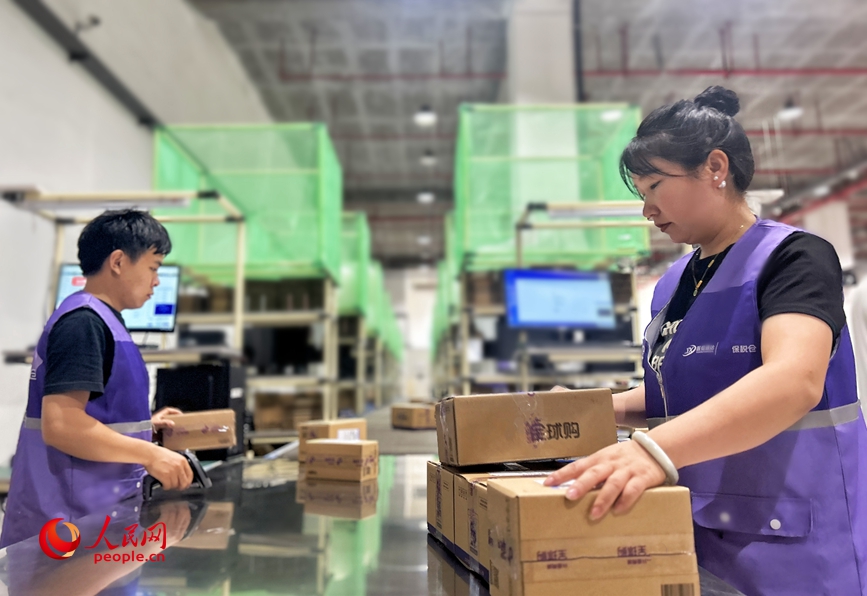 Para pekerja sedang sibuk bertugas untuk mengisih dan memproses bungkusan di dalam gudang bersepadu. (People’s Daily Online/Huo Yaping)