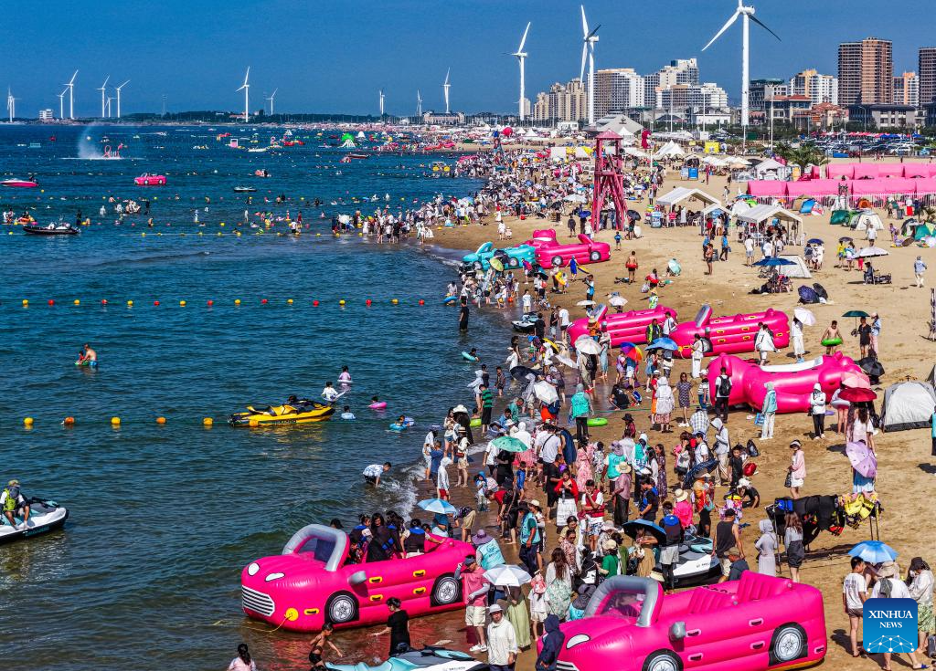 Foto dron bertarikh 12 Julai 2025 ini memperlihatkan pengunjung berseronok di sebuah tapak perkelahan tepi pantai di bandar Rongcheng, provinsi Shandong, timur China. (Foto oleh Li Xinjun/Xinhua)