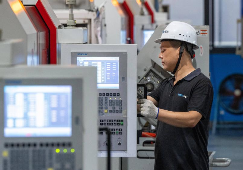 Seorang juruteknik sedang memeriksa peralatan pengeluaran kancing automatik di sebuah bengkel di daerah Zhenhai, Ningbo, Provinsi Zhejiang di timur China. (Foto oleh Hu Xuejun)