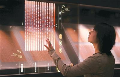 Seorang pengunjung menyentuh sebuah skrin sentuh untuk melihat transkripsi slip buluh di Muzium Jingmen, Jingzhou, Provinsi Hubei di tengah China. (Foto oleh Zhao Ping)