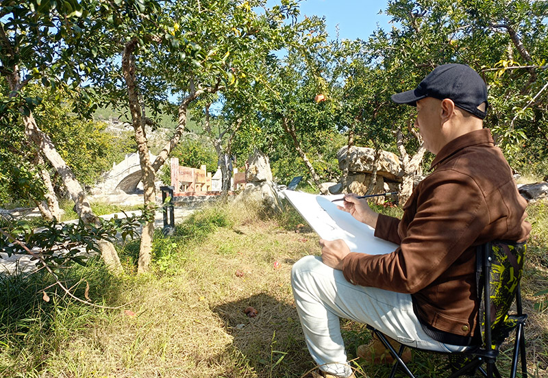 Seorang artis sedang melukis gambar di bawah sebatang pokok delima di Zaozhuang, Provinsi Shandong di timur China. (Foto oleh Zhang Houpeng)