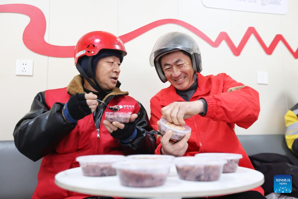 Penghantar makanan merasa bubur Laba yang disediakan oleh sukarelawan komuniti di sebuah stesen kurier di bandar Huzhou, provinsi Zhejiang, timur China, 26 Januari 2026. (Ni Lifang/Xinhua)