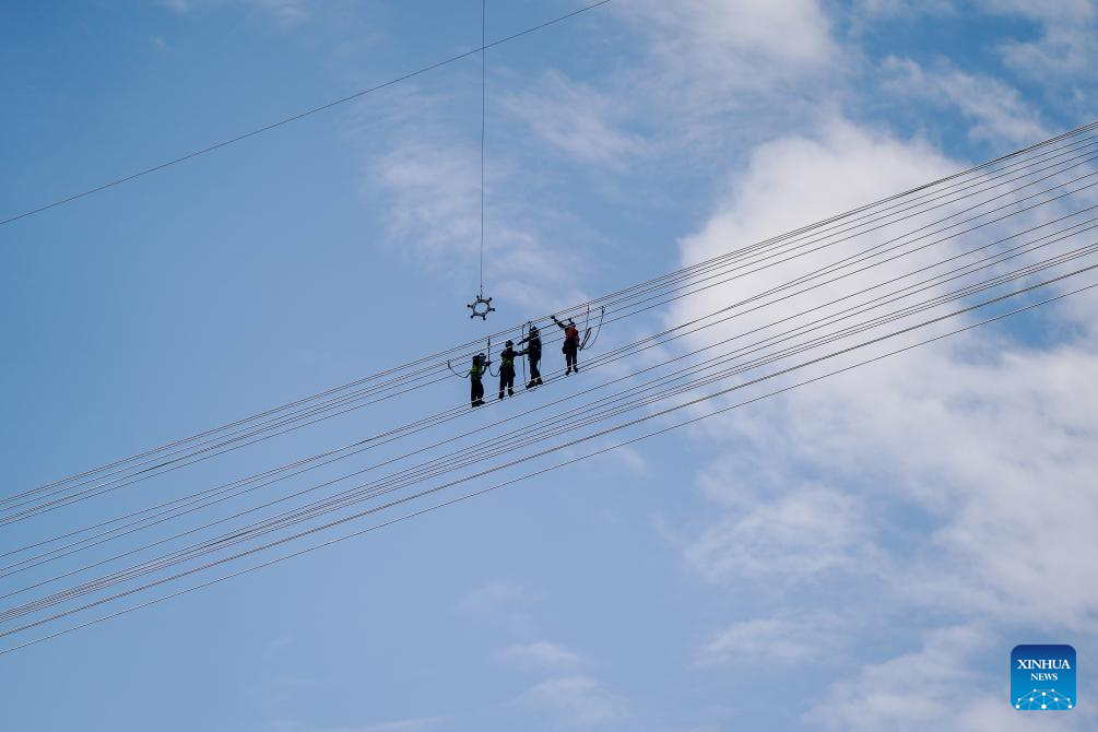 Pekerja pembinaan berjabat tangan selepas siapnya kerja penyambungan talian di tempat pertemuan seksyen China dan Laos bagi projek ketersambungan kuasa 500kV China-Laos, 5 Februari 2026. (Xinhua/Peng Yikai) 