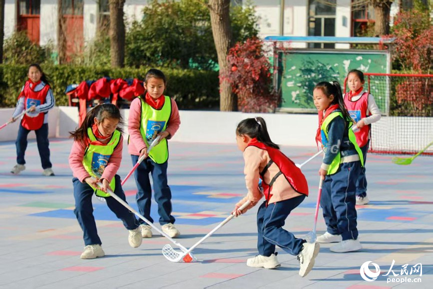 Budak-budak perempuan bermain floorball di padang Sekolah Rendah Sanhetou, pekan Chenqiao, kaunti Fengqiu di provinsi Henan, tengah China. (People's Daily Online/Cheng Minghui)