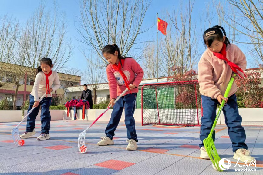 Budak-budak perempuan bermain floorball di padang Sekolah Rendah Sanhetou, pekan Chenqiao, kaunti Fengqiu di provinsi Henan, tengah China. (People's Daily Online/Cheng Minghui)