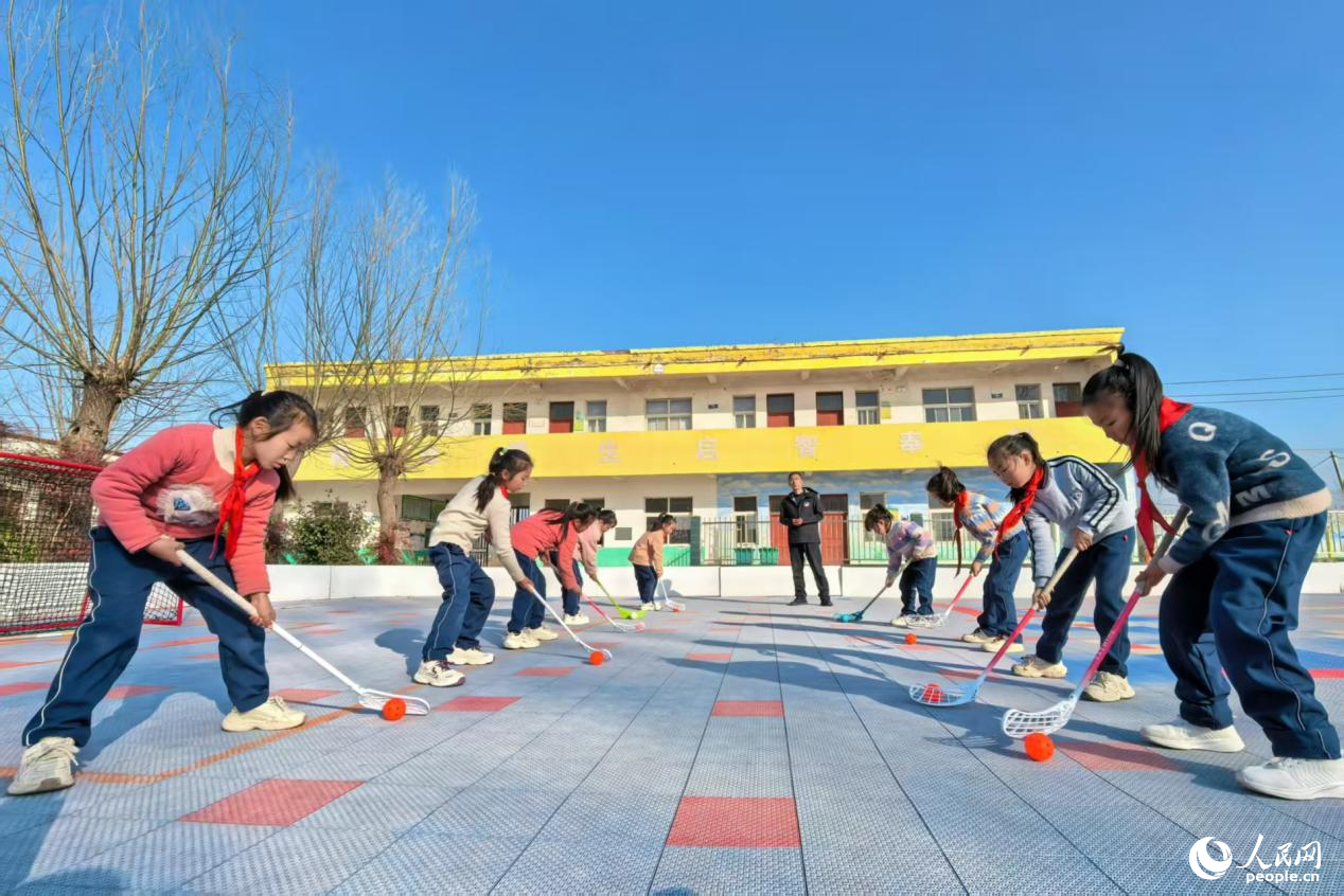 Budak-budak perempuan bermain floorball di padang Sekolah Rendah Sanhetou, pekan Chenqiao, kaunti Fengqiu di provinsi Henan, tengah China. (People's Daily Online/Cheng Minghui)