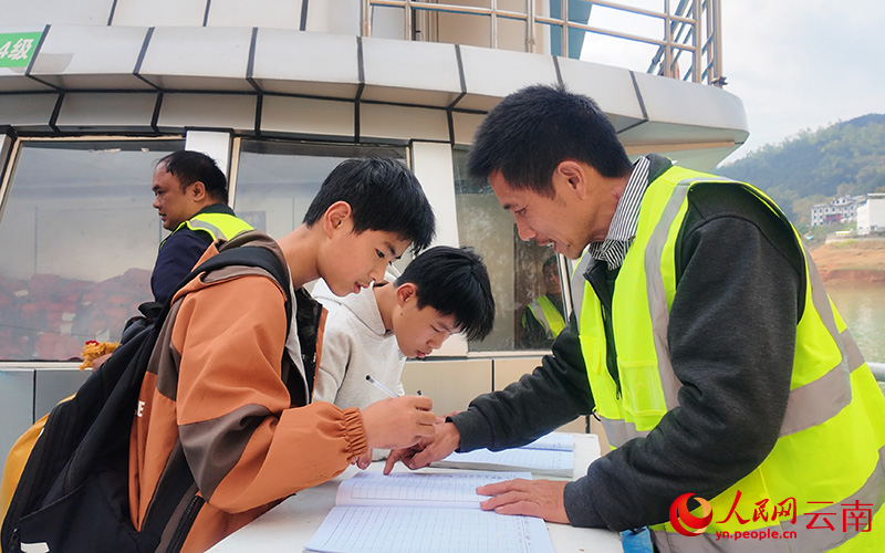 Seorang pekerja membantu pelajar mendaftar diri sebelum menaiki kapal sekolah Wanfeng No. 1 di pekan Lubuge, kaunti Luoping, provinsi Yunnan, barat daya China. (People's Daily Online/Liu Yi)