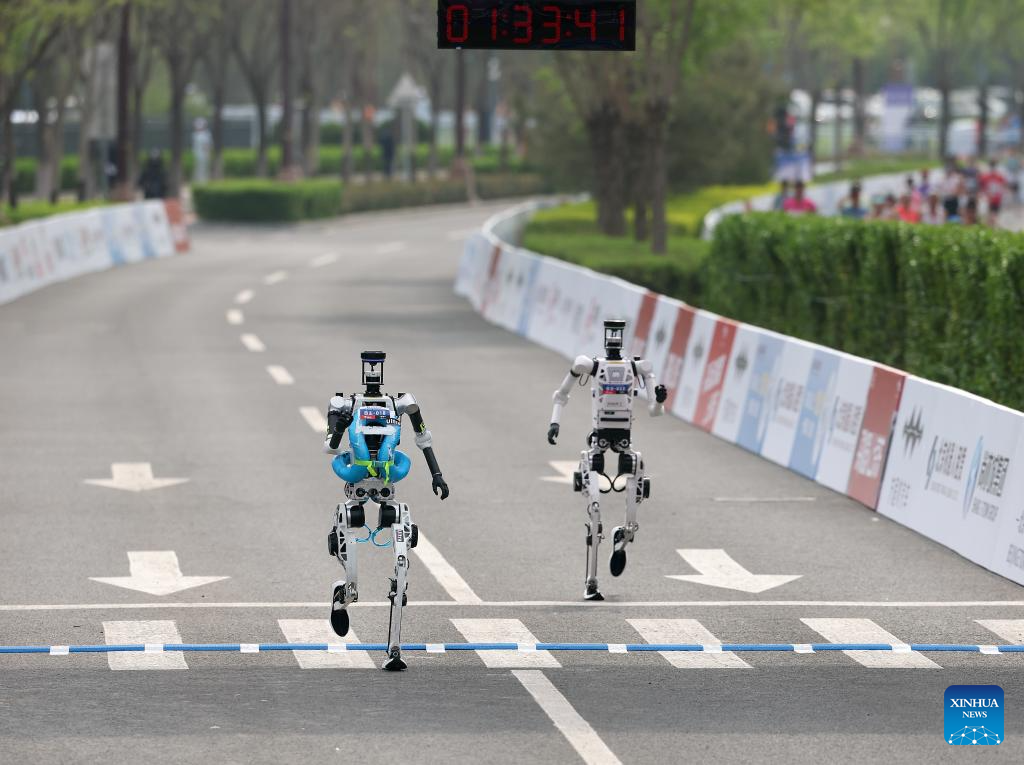 Robot manusia "Tiangong 1.0 Ultra" (kiri) yang mewakili Pasukan Tianxiao dalam kategori berautonomi, berlari pada separuh maraton E-Town Beijing dan separuh maraton robot manusia di Kawasan Pembangunan Ekonomi-Teknologi Beijing di tenggara Beijing, China, 19 April 2026. (Xinhua/Zhang Chenlin)