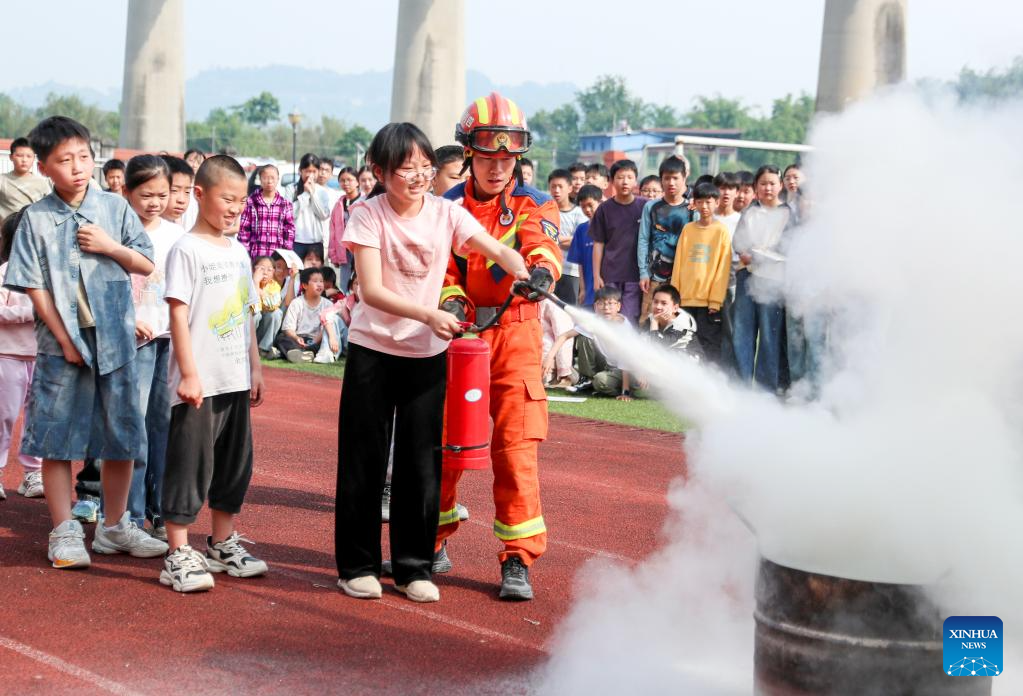 Ahli bomba mengajar pelajar menggunakan pemadam kebakaran di sebuah sekolah rendah di Huaying, provinsi Sichuan, barat daya China, 11 Mei 2026. (Qiu Haiying/Xinhua)