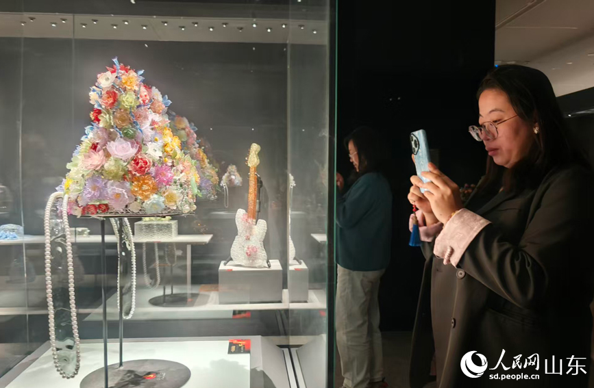 Pelancong mengambil gambar hiasan kepala bunga sepuh berwarna di Muzium Seramik dan Kaca China di Zibo, provinsi Shandong, timur China. (People's Daily Online/Song Cui)