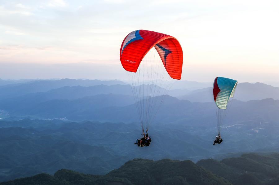 Foto dron bertarikh 30 Julai 2026 ini menunjukkan pelancong meluncur layar bersama peluncur profesional di sebuah pangkalan di pekan Jiuzhou, kaunti Huangping, provinsi Guizhou, barat daya China. (Xinhua/Yang Wenbin)