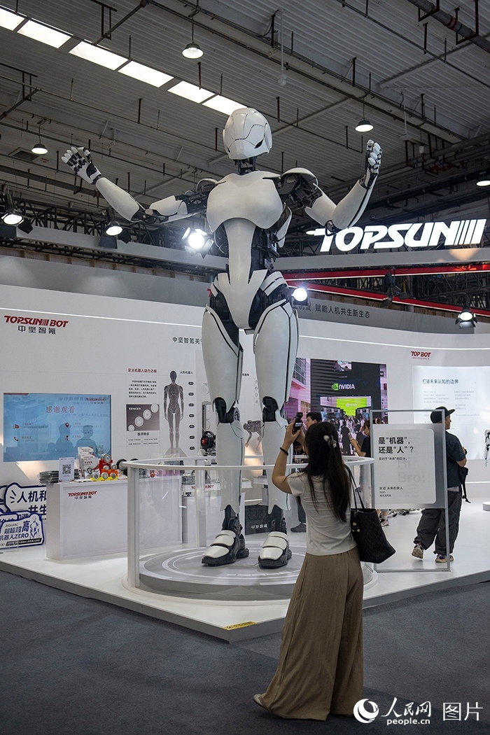 Seorang wanita mengambil gambar robot manusia gergasi pada Persidangan Robot Dunia 2026 di Beijing, 19 Ogos 2026. (People's Daily Online/Weng Qiyu)