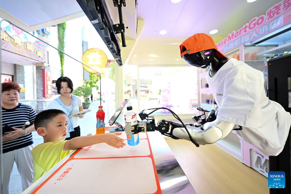 Sebuah robot mengambil sebotol minuman elektrolit dan memberikan kepada pelanggan di sebuah kedai robot pintar terkandung di Jalan Leijie, Hefei, provinsi Anhui, timur China, 26 Ogos 2026. (Xinhua/Zhou Mu)