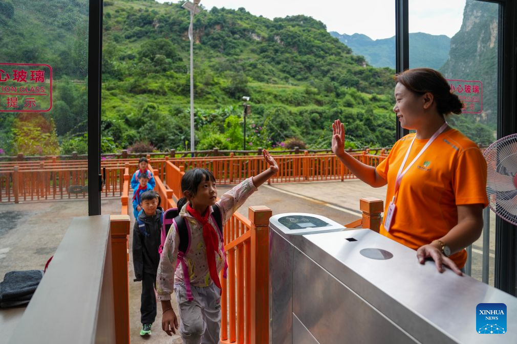 Pelajar menyapa seorang pekerja sebelum menaiki lif cenuram di pekan Puli, bandar Xuanwei, provinsi Yunnan, barat daya China, 30 Ogos 2026. (Xinhua/Chen Xinbo)