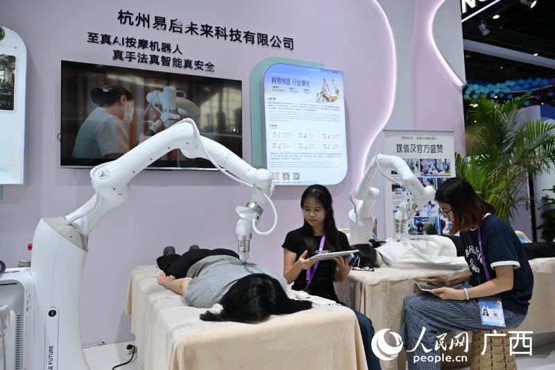 Pelawat menikmati pengalaman urutan robot AI. Foto oleh Lei Qijun, People's Daily Online