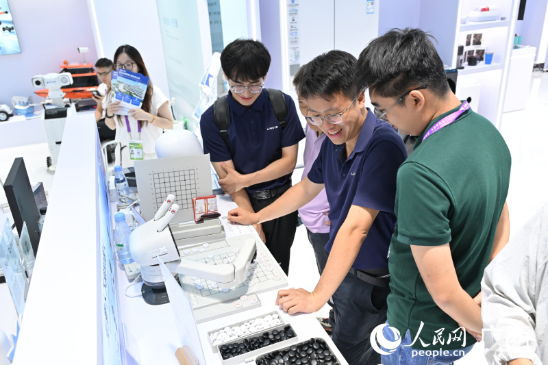 Pelawat bermain catur dengan robot AI. Foto oleh Lei Qijun, People's Daily Online