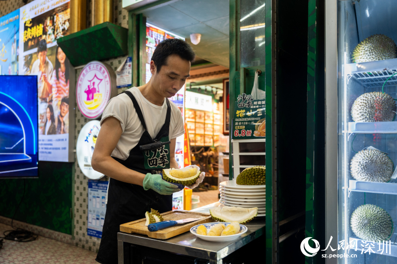 Seorang kakitangan membuka sebiji durian segar. (People's Daily Online/Wang Xing)