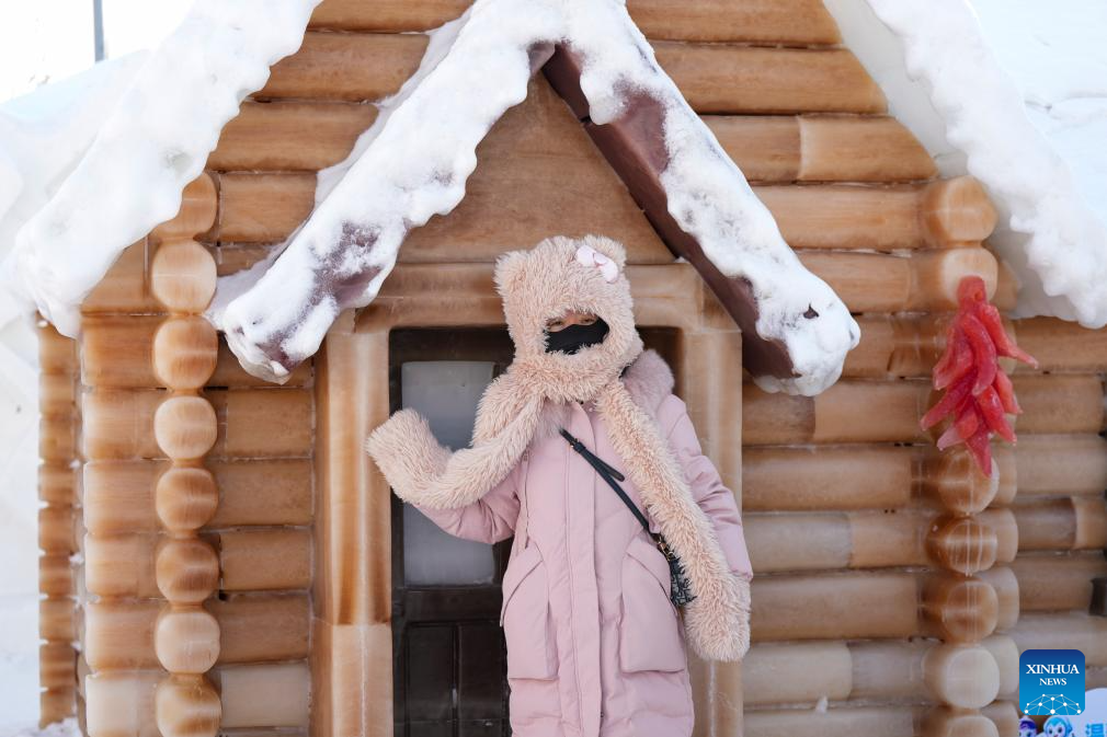 Seorang pengunjung bergambar di depan sebuah rumah ais yang dicelup pewarna tumbuhan di Dunia Ais dan Salji Harbin, provinsi Heilongjiang, timur laut China, 28 Januari 2026. (Xinhua/Wang Song)