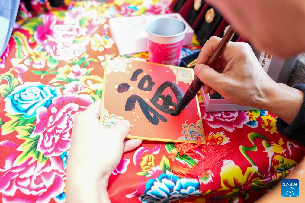 Seorang pelayan menulis karakter “Fu” (tuah) di sebuah “bazar dalam tren” di provinsi Heilongjiang, timur laut China, 4 Februari 2026. (Xinhua/Wang Song)