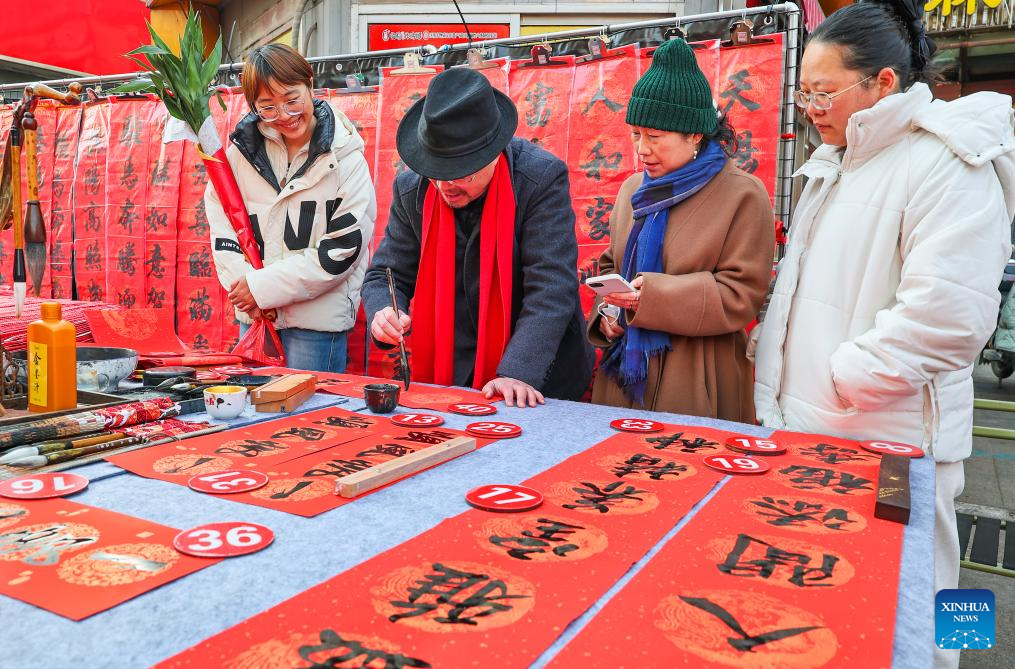 Seorang peminat kaligrafi menulis kuplet untuk pelanggan di sebuah pasar di bandar Lianyungang, provinsi Jiangsu, timur China, 13 Februari 2026. (Foto oleh Wang Jianmin/Xinhua)