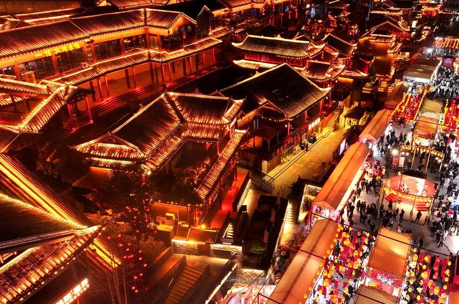 Foto dron bertarikh 17 Februari 2026 menunjukkan pelancong mencuba juadah tempatan di sebuah jalan snek di kaunti Xuan’en, provinsi Hubei, tengah China. Pada Tahun Baharu Cina, tanglung menghiasi seluruh kaunti, menambah kemeriahan suasana perayaan. (Foto oleh Song Wen/Xinhua)