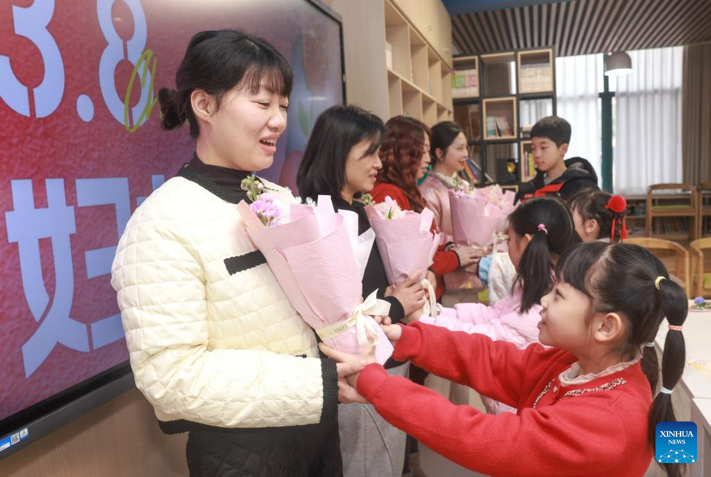 Murid-murid menghadiahkan bunga kepada ibu mereka pada acara sambutan Hari Wanita Antarabangsa di sebuah sekolah rendah di daerah Hongshan, Wuhan, provinsi Hubei, tengah China, 8 Mac 2026. (Foto oleh Zhao Jun/Xinhua)