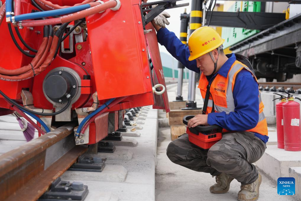 Seorang pekerja menyah pepijat alat kimpal temu kilat kuasa baharu untuk pelbagai senario di tapak pembinaan Kereta Api Subbandar Hangzhou-Deqing di provinsi Zhejiang, timur China, 22 Mac 2026. (Xinhua/Huang Zongzhi)